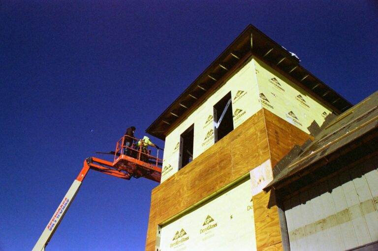 Operatore nel cestello di una piattaforma elevabile mentre lavora su un edificio